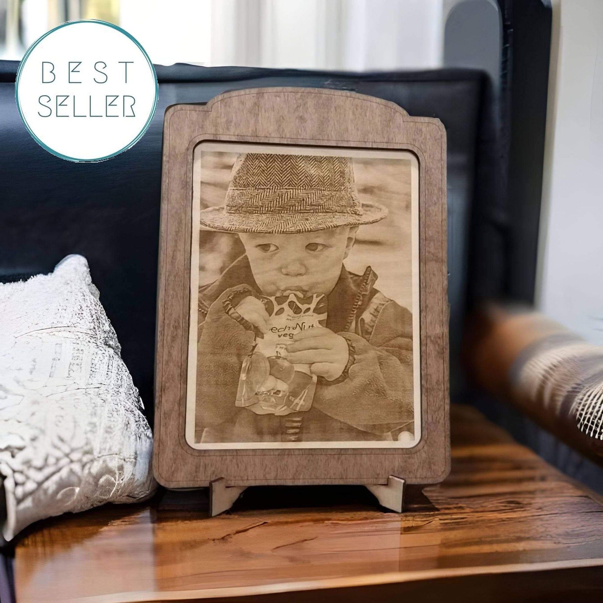 “Best Seller” badge overlaying a wooden picture frame with a sepia-toned photo of a child holding a juice, placed on a dark leather surface with throw pillows in the background; forged art; Photo Engrave - Premium Photo from Forged ARTolley - Just $62.99! Shop now at Forged ARTolley